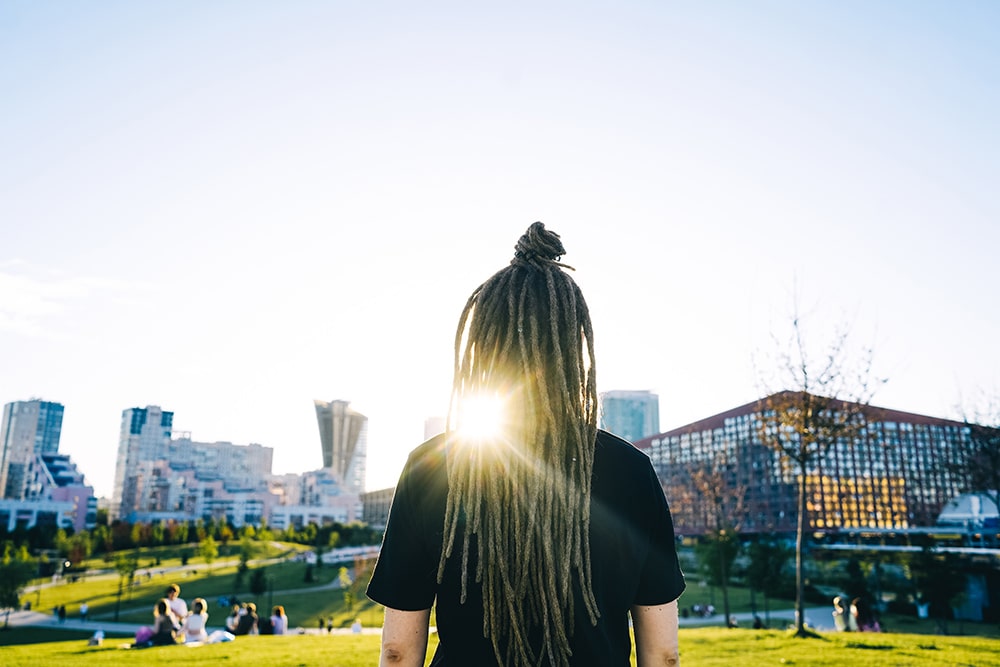 Rear view young woman with dreadlocks in park.